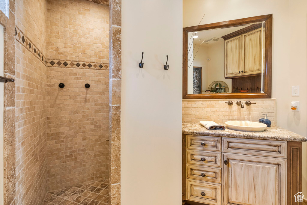 Full bathroom with tiled shower, vanity, and backsplash