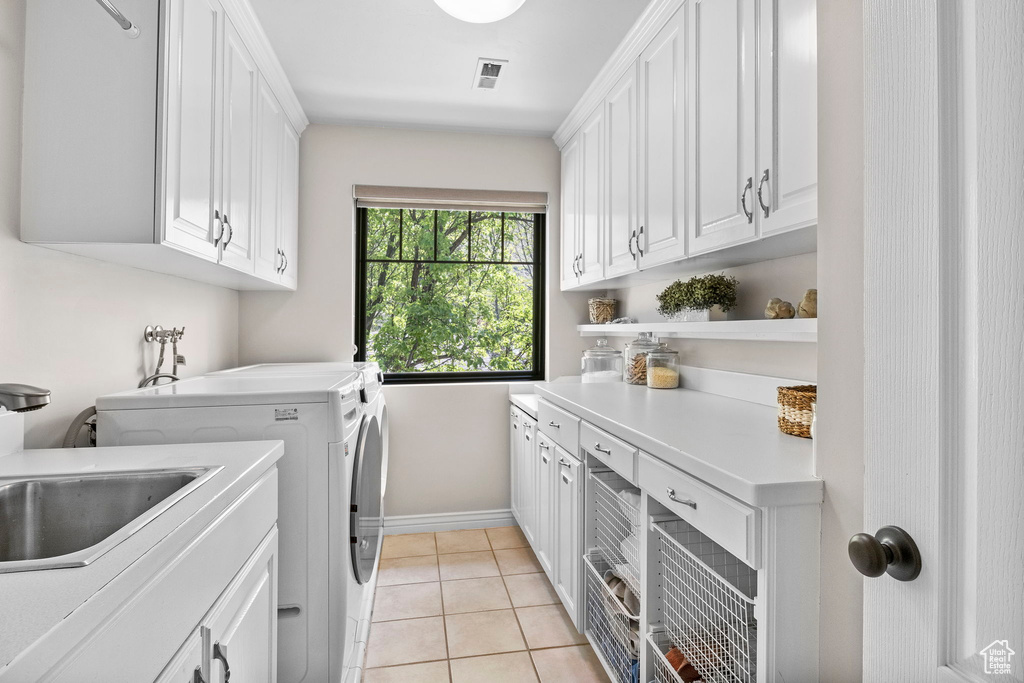 Laundry room with cabinet space, washer and dryer, baseboards, and light tile patterned flooring