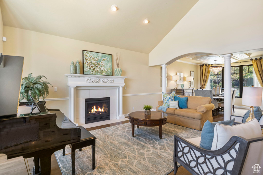 Living room featuring decorative columns, arched walkways, wood finished floors, recessed lighting, and lofted ceiling