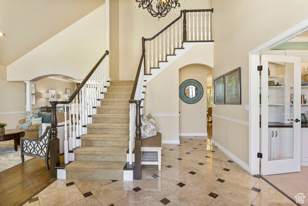 Tiled entryway featuring arched walkways, a towering ceiling, stairway, baseboards, and inlaid floor details