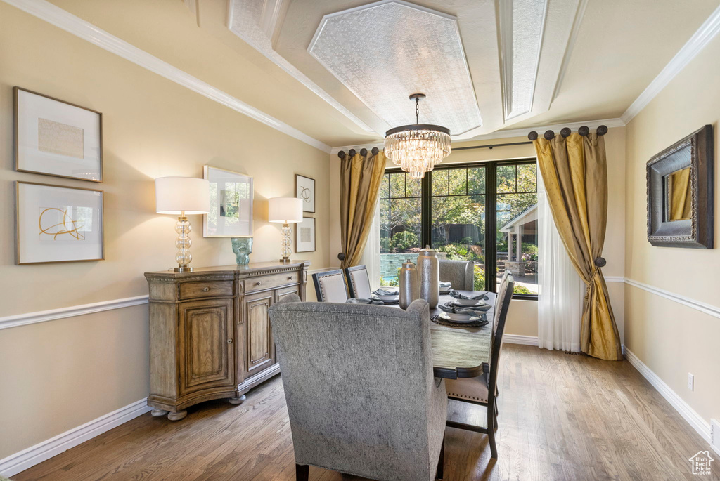 Dining room featuring a chandelier, light wood finished floors, baseboards, and ornamental molding