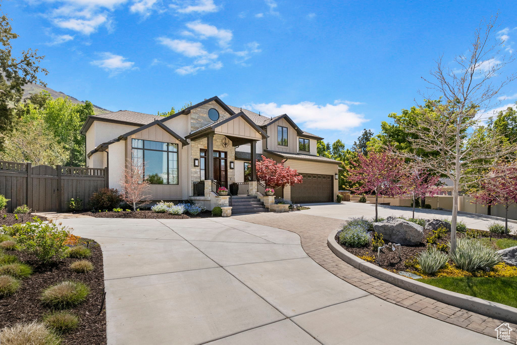 View of front facade featuring fence, concrete driveway, a garage, and board and batten siding