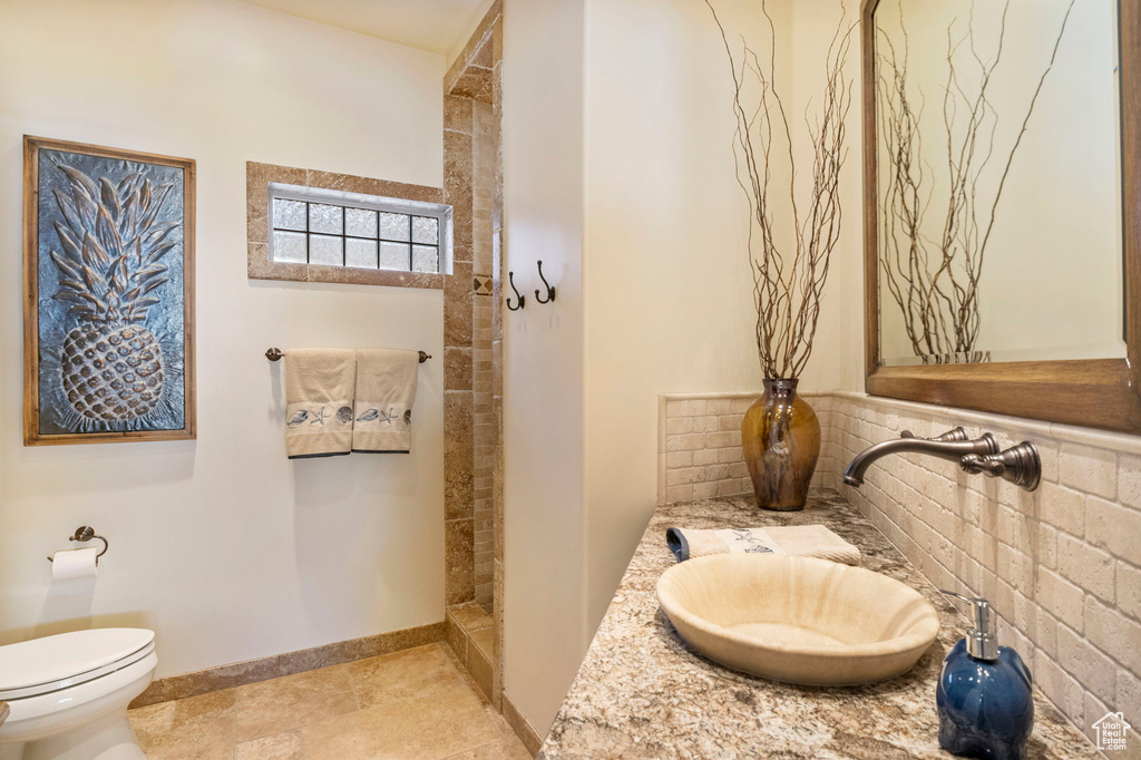Bathroom with toilet, a walk in shower, tasteful backsplash, vanity, and baseboards