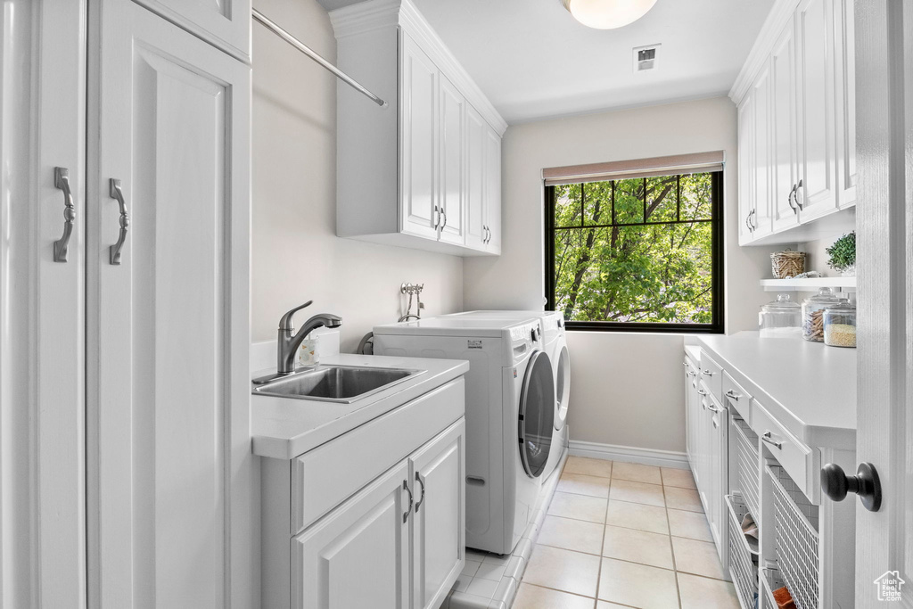 Washroom with cabinet space, separate washer and dryer, baseboards, and light tile patterned flooring