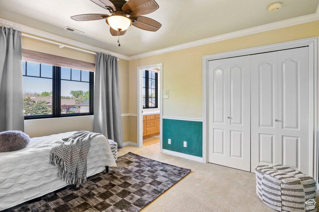 Bedroom with light colored carpet, crown molding, a closet, baseboards, and ensuite bath