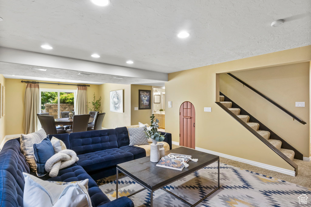 Carpeted living room featuring baseboards, stairs, and recessed lighting