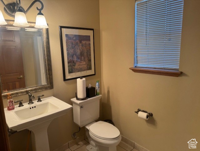 Bathroom with tile patterned floors, a sink, toilet, baseboards, and a chandelier