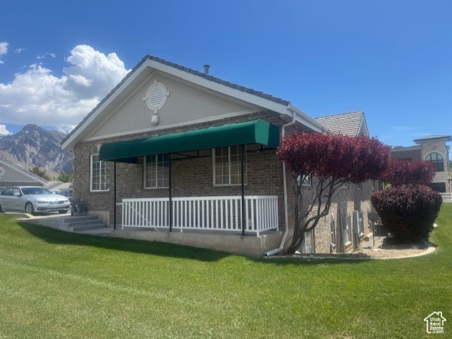 View of front of home featuring covered porch, a front lawn, and brick siding