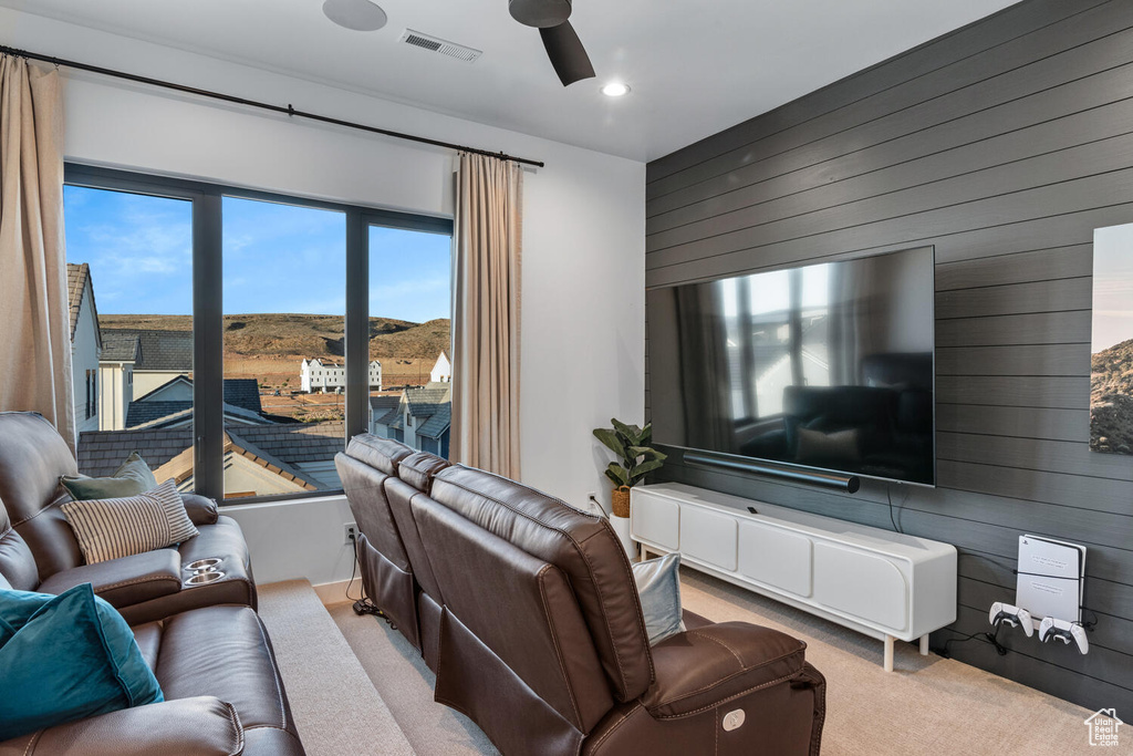 Living area with wooden walls, carpet flooring, ceiling fan, and recessed lighting