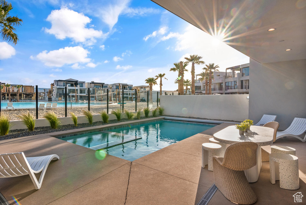 View of swimming pool featuring a pool with connected hot tub, fence, and a patio area