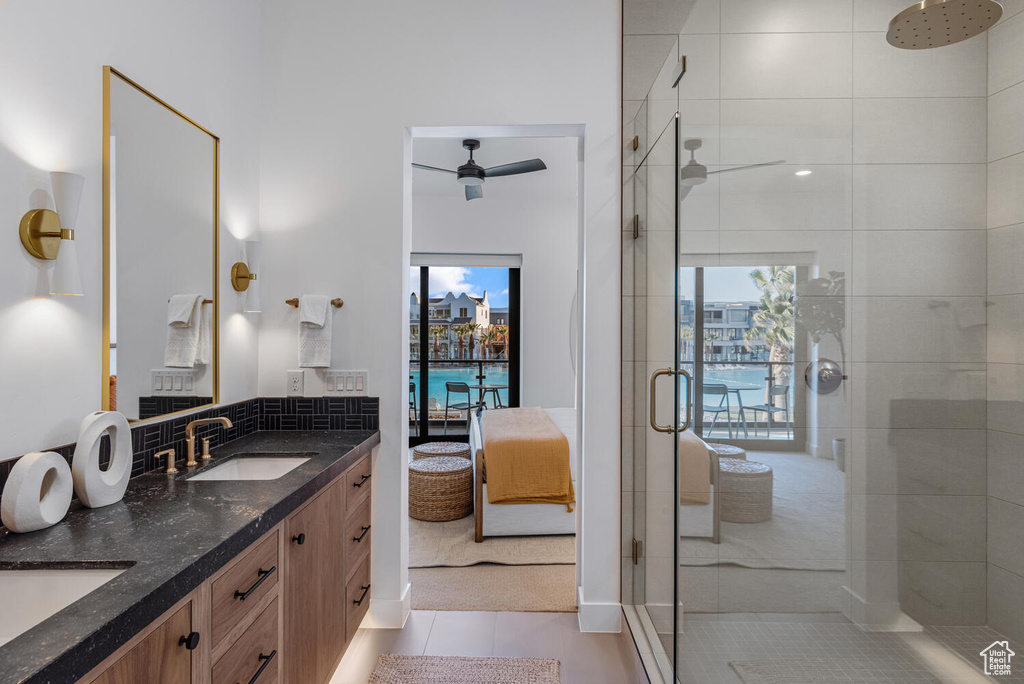 Ensuite bathroom featuring a stall shower, tile patterned floors, double vanity, and a ceiling fan