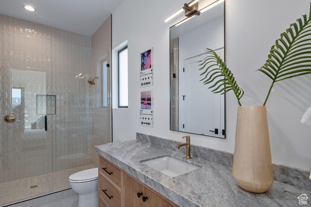 Bathroom with a tile shower, toilet, vanity, and recessed lighting