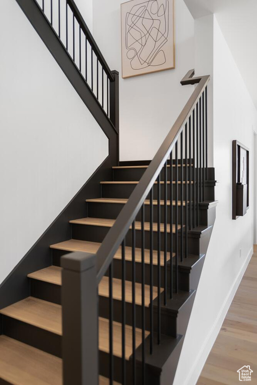 Staircase with wood finished floors and baseboards