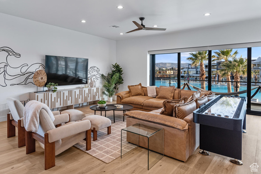 Living area featuring light wood-style flooring, a ceiling fan, and recessed lighting