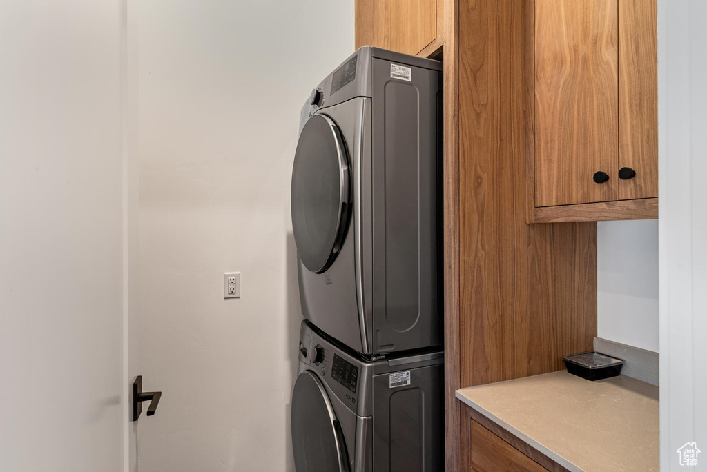 Laundry room featuring cabinet space and stacked washer / dryer