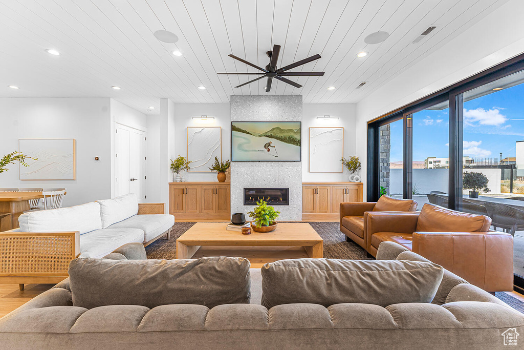 Living area featuring a ceiling fan, recessed lighting, wood finished floors, a large fireplace, and wood ceiling