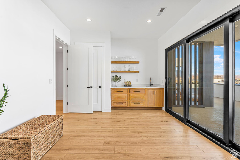 Indoor wet bar featuring light wood-style flooring and recessed lighting
