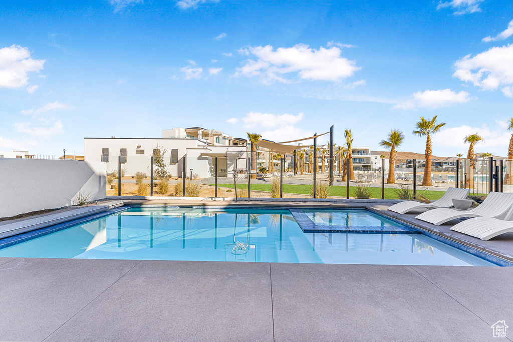 View of pool featuring a residential view, a pool with connected hot tub, and fence