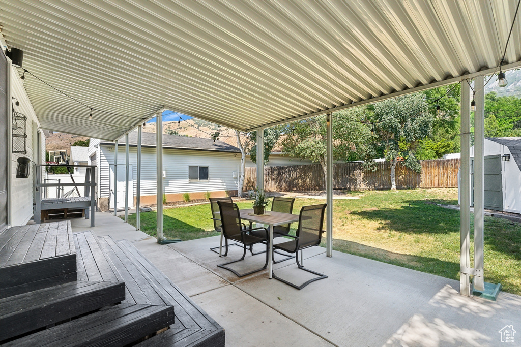 View of patio / terrace with an outdoor structure, outdoor dining area, a deck, and a shed