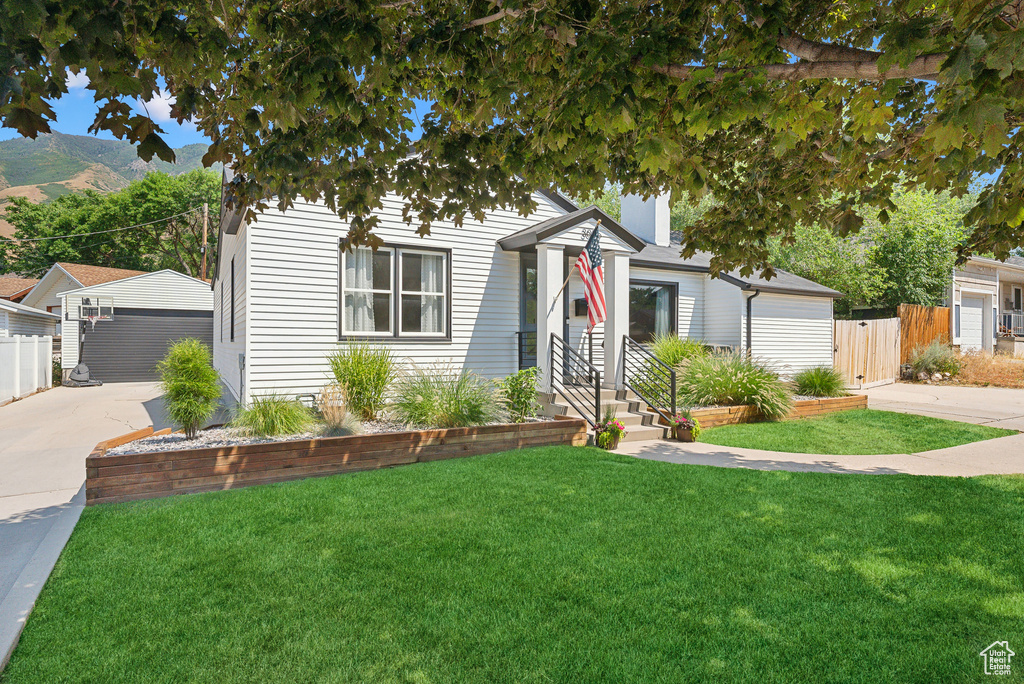 View of front of property with a mountain view, an outdoor structure, and a detached garage
