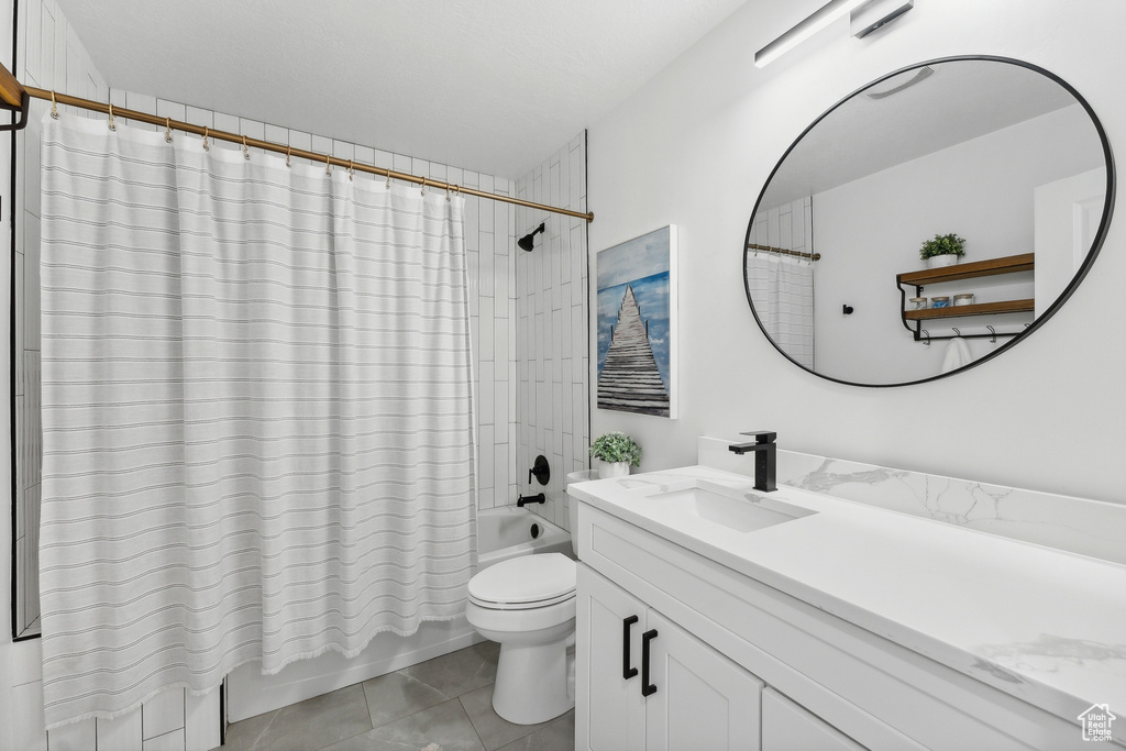 Bathroom featuring shower / bath combination with curtain, vanity, toilet, and tile patterned floors