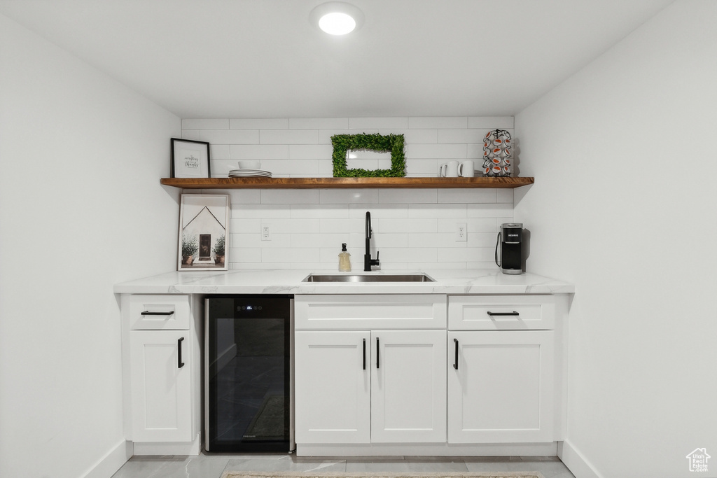 Indoor wet bar with beverage cooler, baseboards, and tasteful backsplash