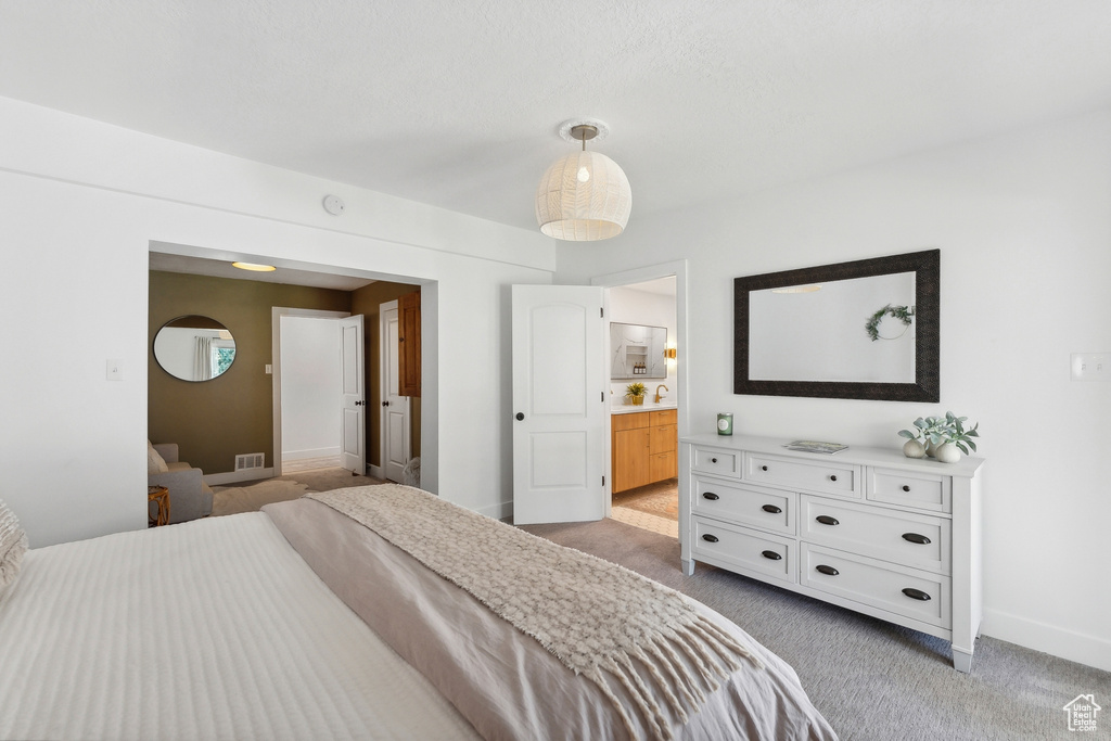 Bedroom featuring light carpet, baseboards, and connected bathroom