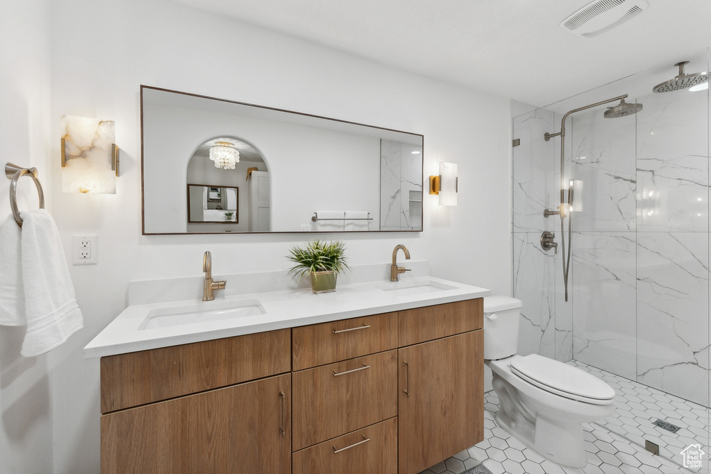 Full bath featuring toilet, a marble finish shower, double vanity, and tile patterned flooring