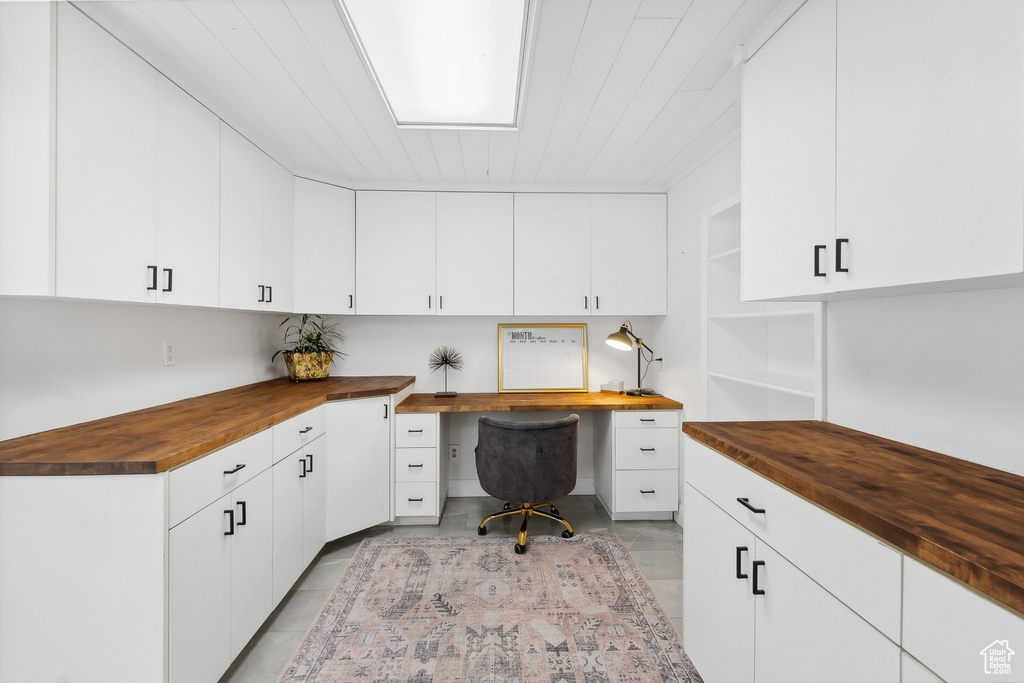 Home office with built in desk, light tile patterned floors, and wood ceiling