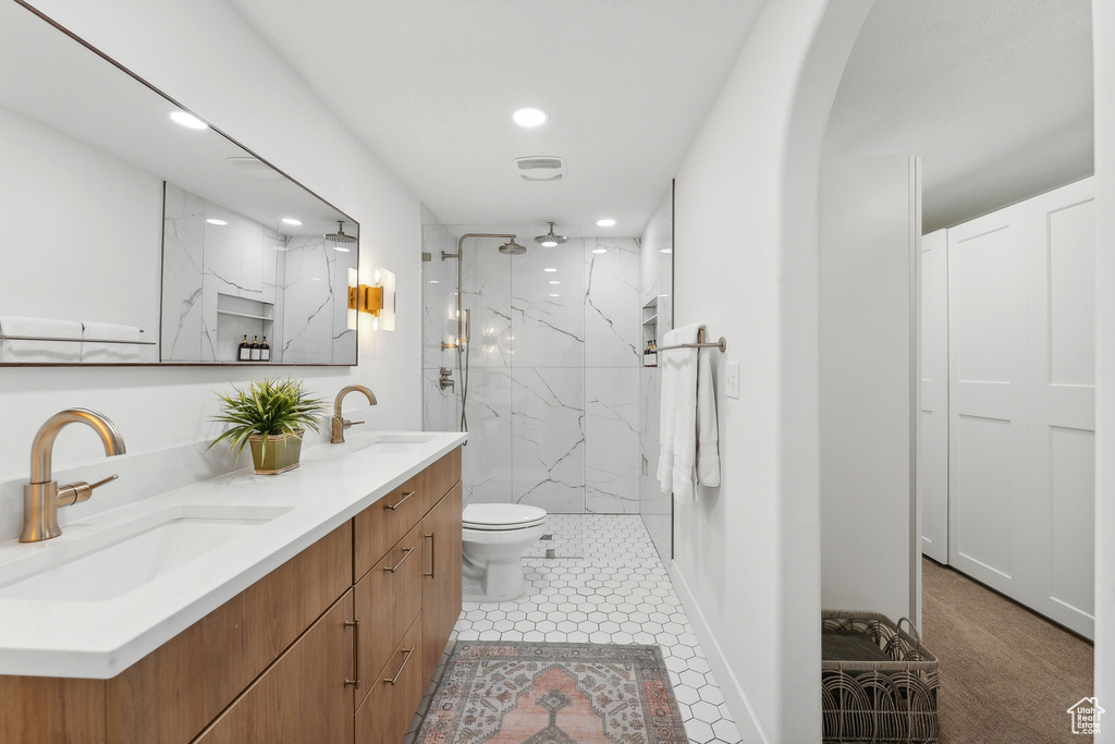 Full bath with recessed lighting, a marble finish shower, double vanity, and toilet