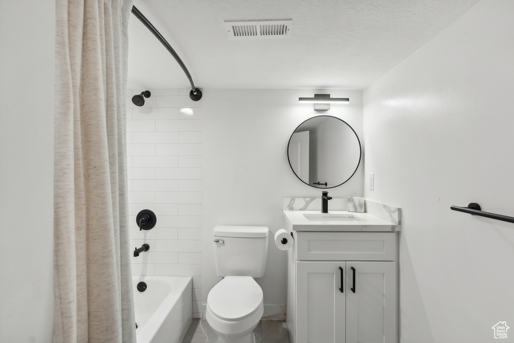 Bathroom featuring toilet, vanity, and shower / tub combo