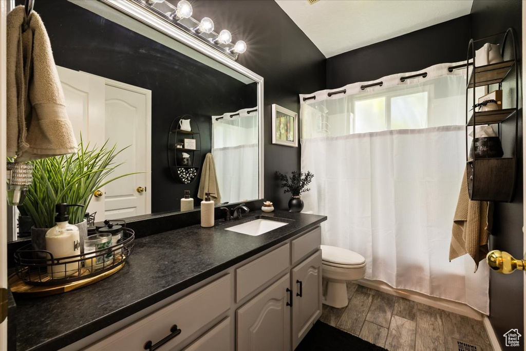 Full bath with wood finished floors, toilet, vanity, and a shower with curtain