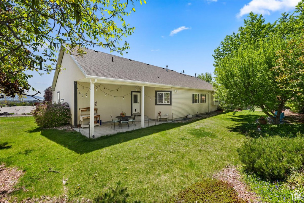 Back of property featuring a patio area, a yard, and stucco siding