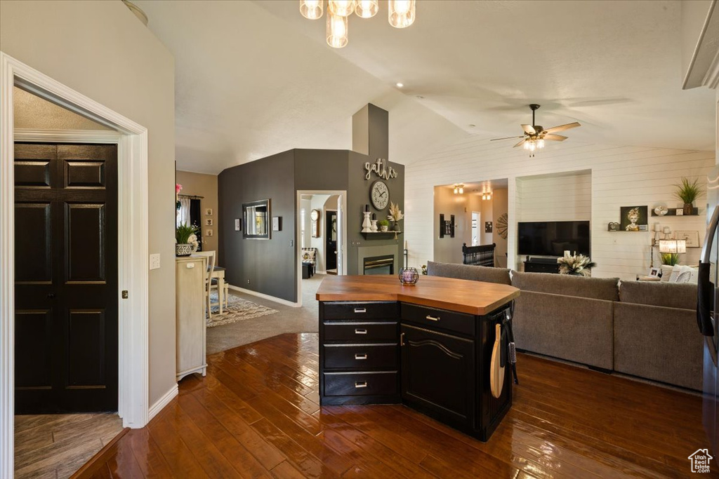 Kitchen featuring butcher block counters, a fireplace, dark cabinets, a ceiling fan, and lofted ceiling