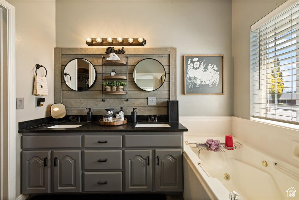 Full bath with healthy amount of natural light, double vanity, and a whirlpool tub