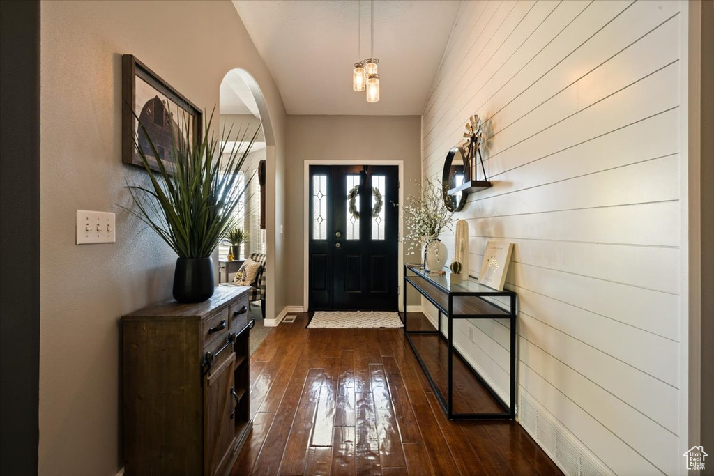 Entrance foyer featuring arched walkways, dark wood-style flooring, and baseboards
