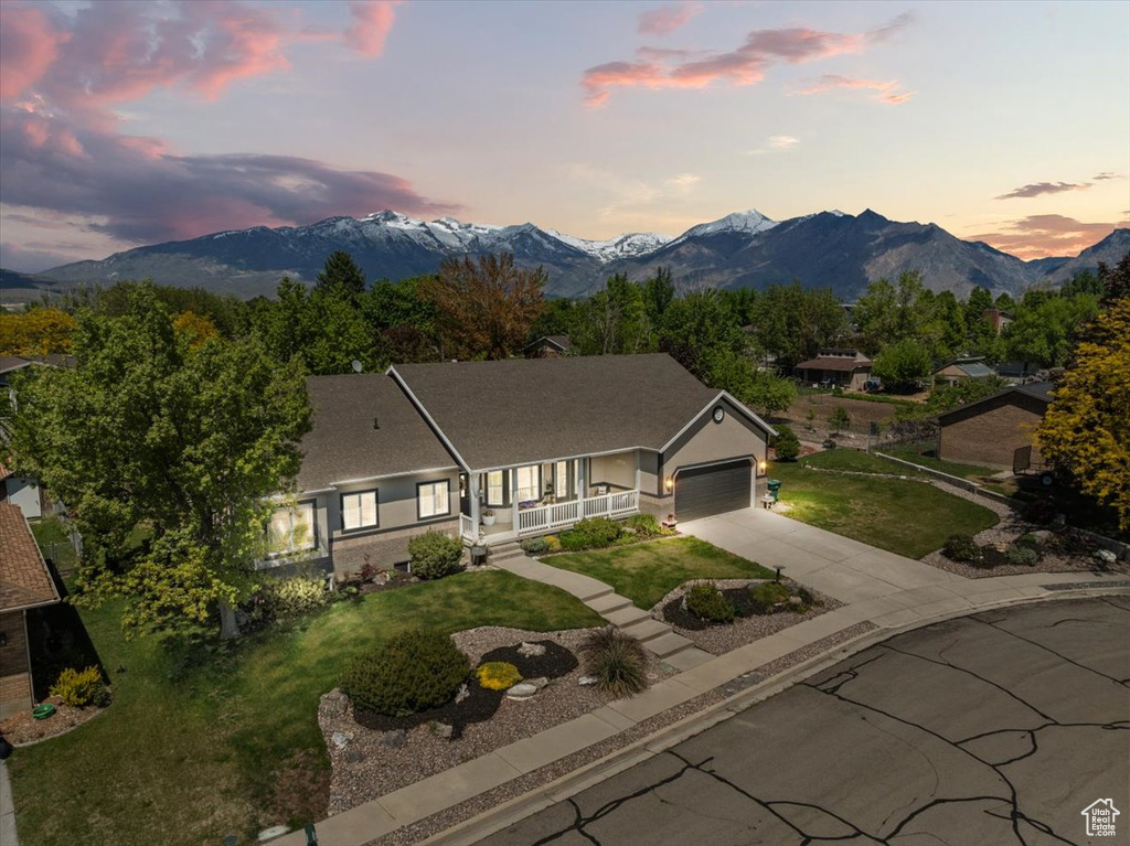 Ranch-style home with a porch, an attached garage, driveway, and a mountain view
