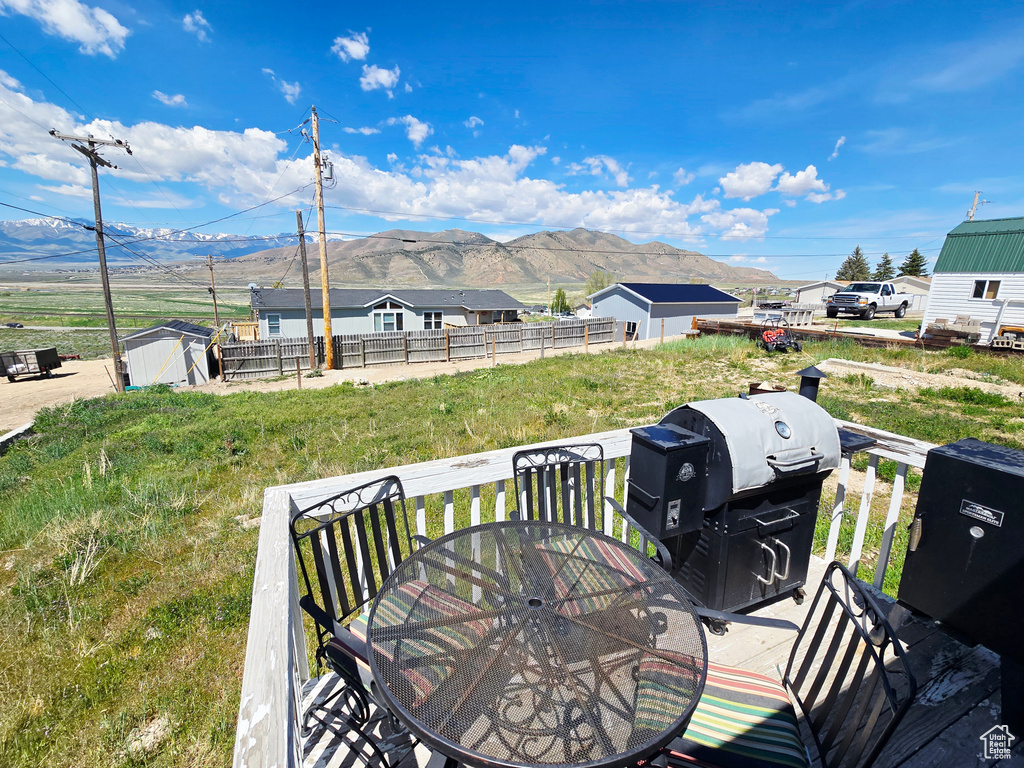 Wooden terrace with a mountain view, outdoor dining space, a storage shed, and an outdoor structure
