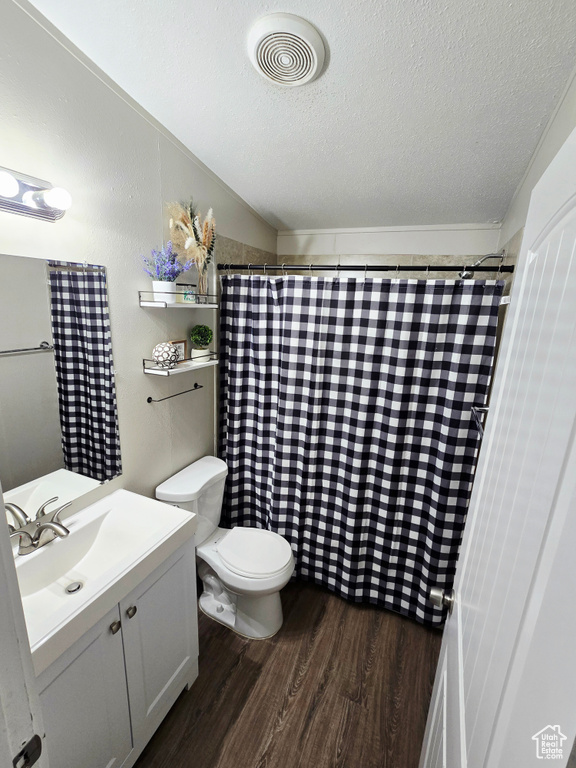 Full bathroom featuring wood finished floors, a textured ceiling, vanity, toilet, and a shower with curtain