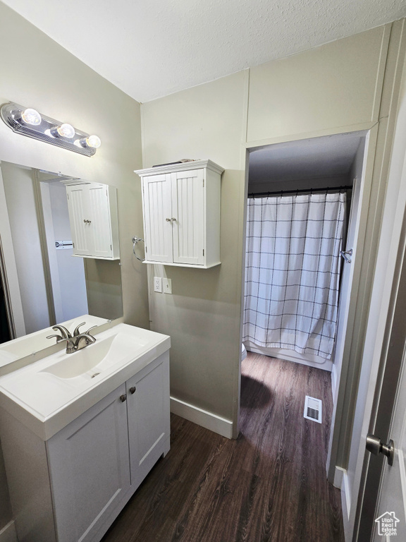 Bathroom with wood finished floors, vanity, a textured ceiling, and baseboards