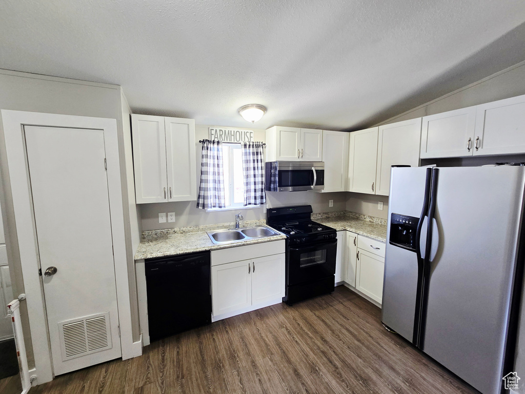 Kitchen featuring black appliances, a sink, white cabinets, dark wood-style floors, and vaulted ceiling