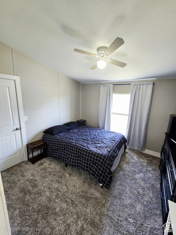 Carpeted bedroom featuring ceiling fan and baseboards