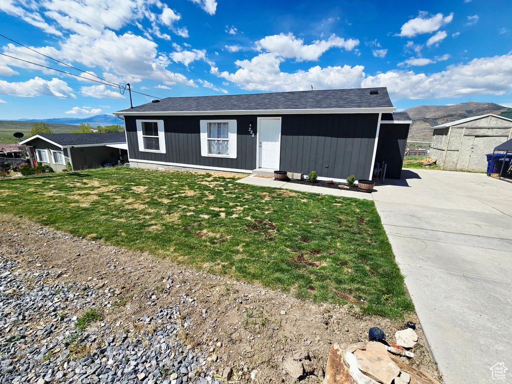 Ranch-style home with a front yard, a mountain view, and driveway