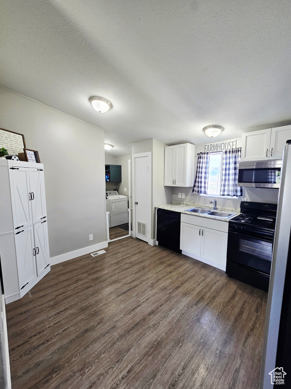 Kitchen featuring black appliances, washing machine and clothes dryer, a sink, dark wood-style flooring, and white cabinetry