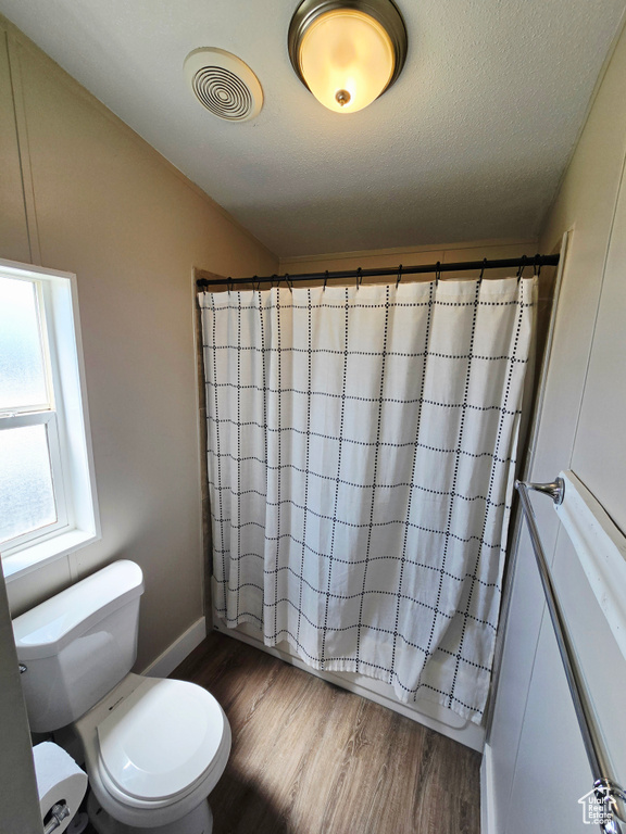 Full bath with wood finished floors, toilet, and baseboards