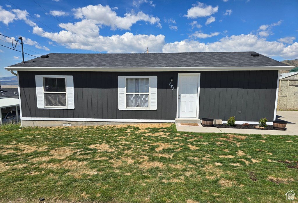 View of front of house with a front lawn and roof with shingles