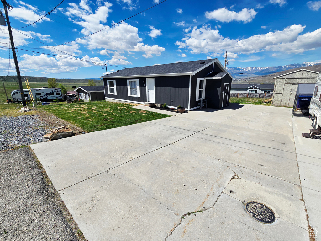 Single story home with a mountain view, driveway, an outdoor structure, and a storage shed