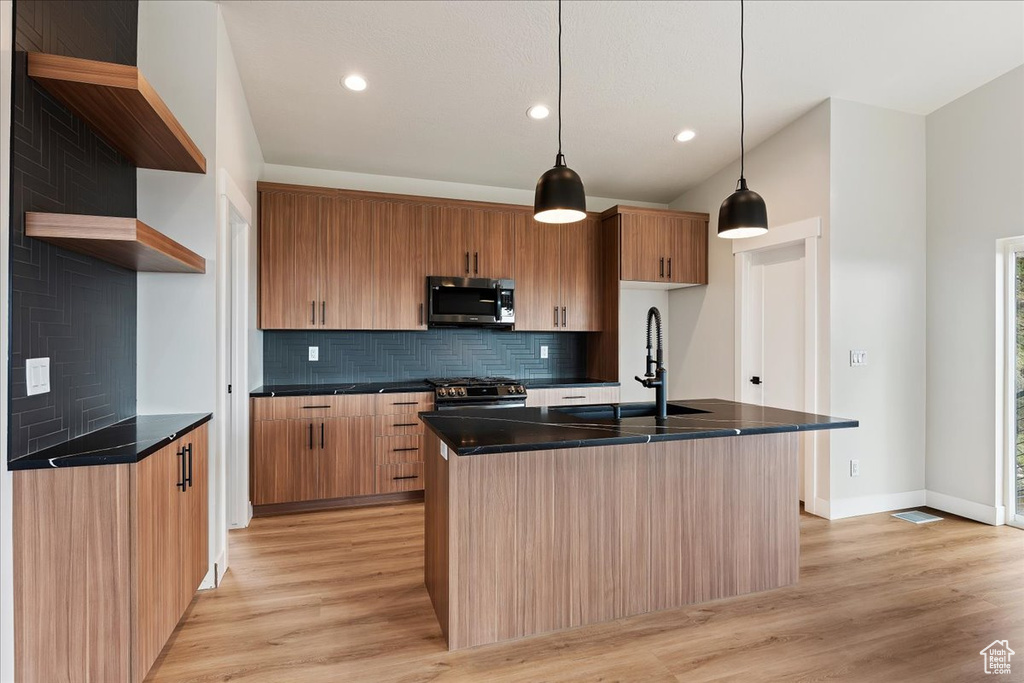 Kitchen featuring stainless steel appliances, a sink, dark countertops, open shelves, and decorative backsplash