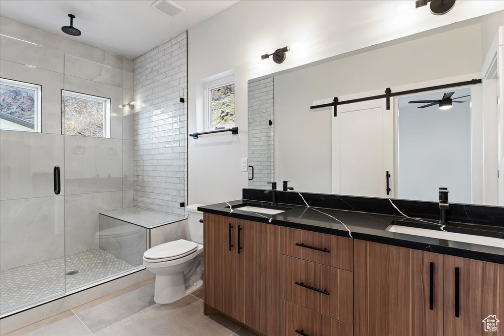 Full bath with a stall shower, toilet, double vanity, and tile patterned floors