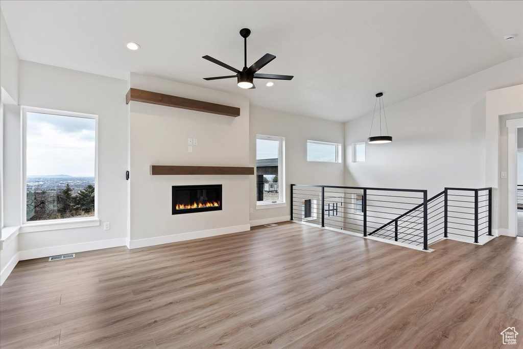 Unfurnished living room featuring a ceiling fan, baseboards, wood finished floors, recessed lighting, and a glass covered fireplace